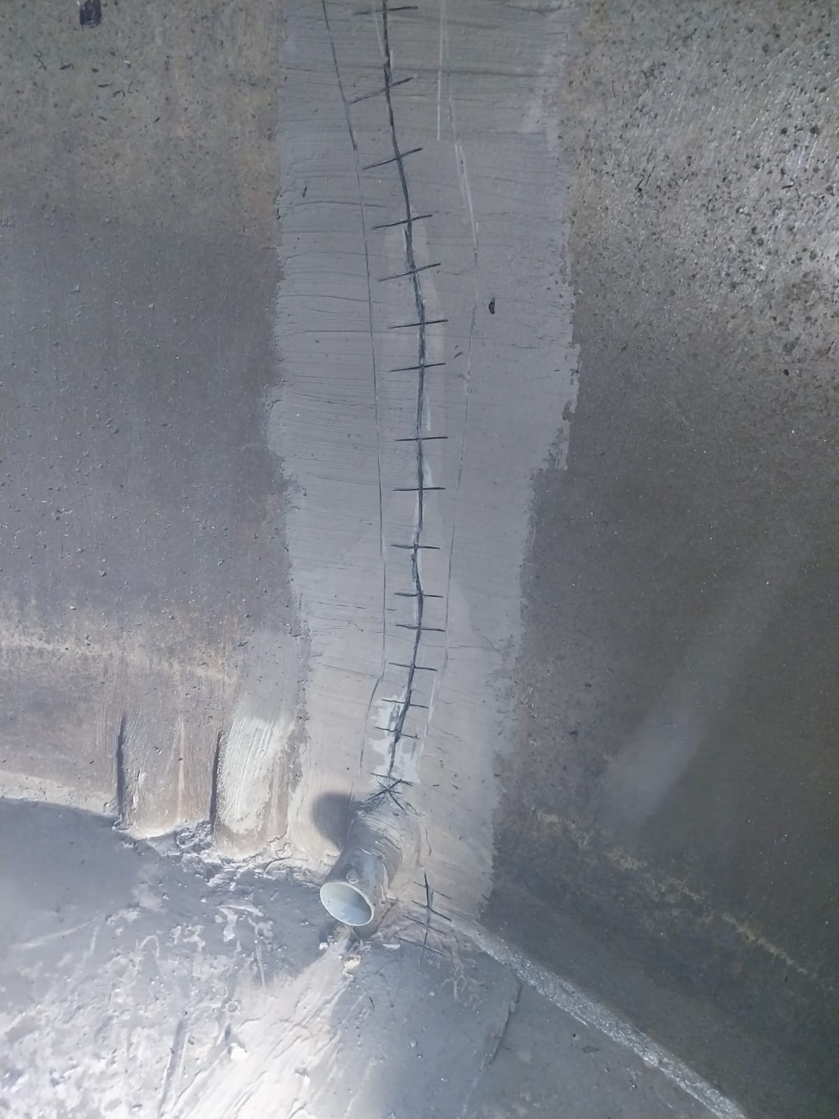 Fissure agrafée en pied de paroi avec traversée PVC